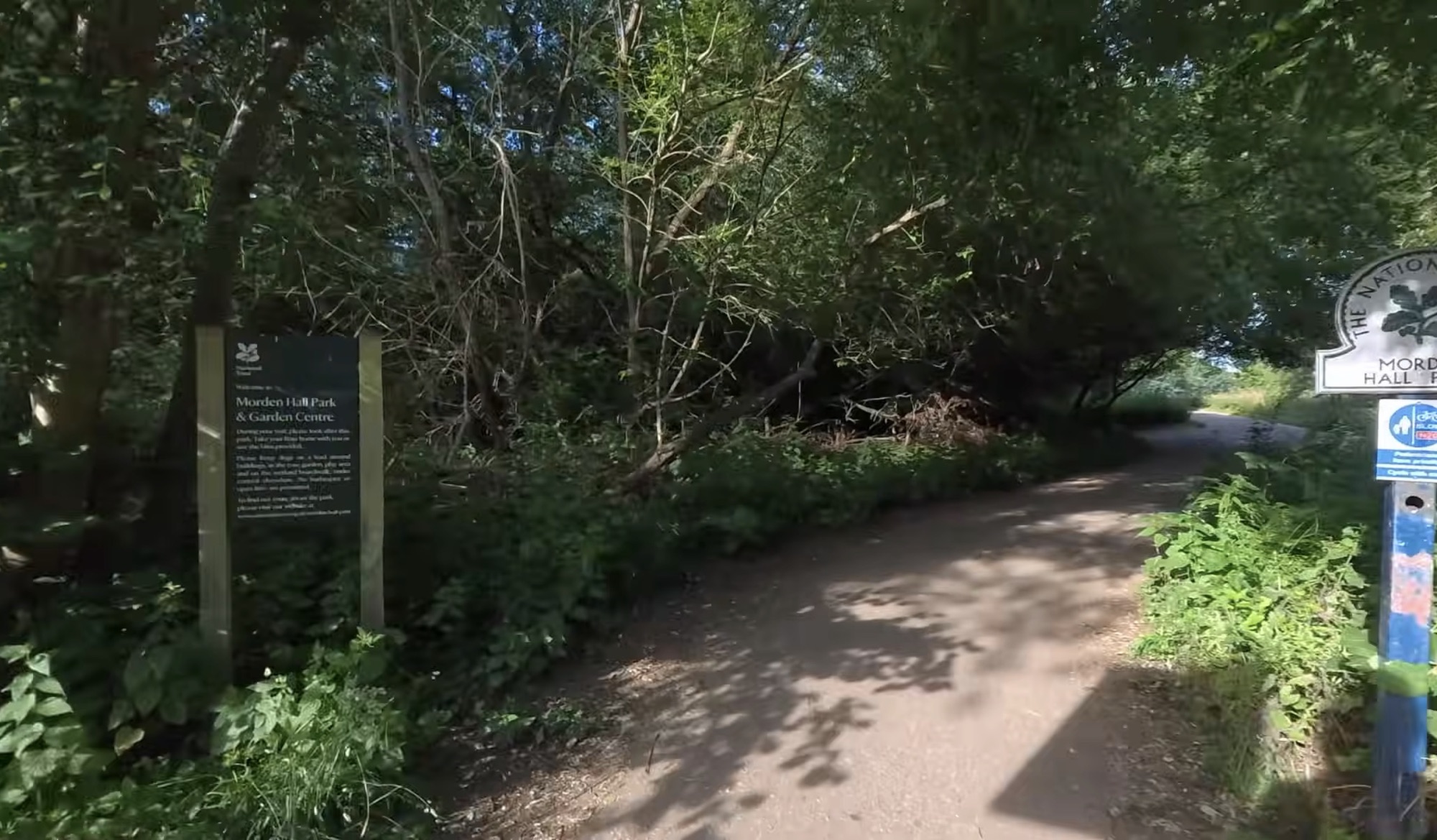 National Trust welcome sign at a Morden Hall Park entrance beside a gravel path