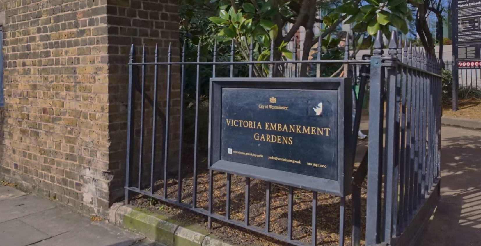 A second Victoria Embankment Gardens entrance sign set into a brick corner wall near the Temple end