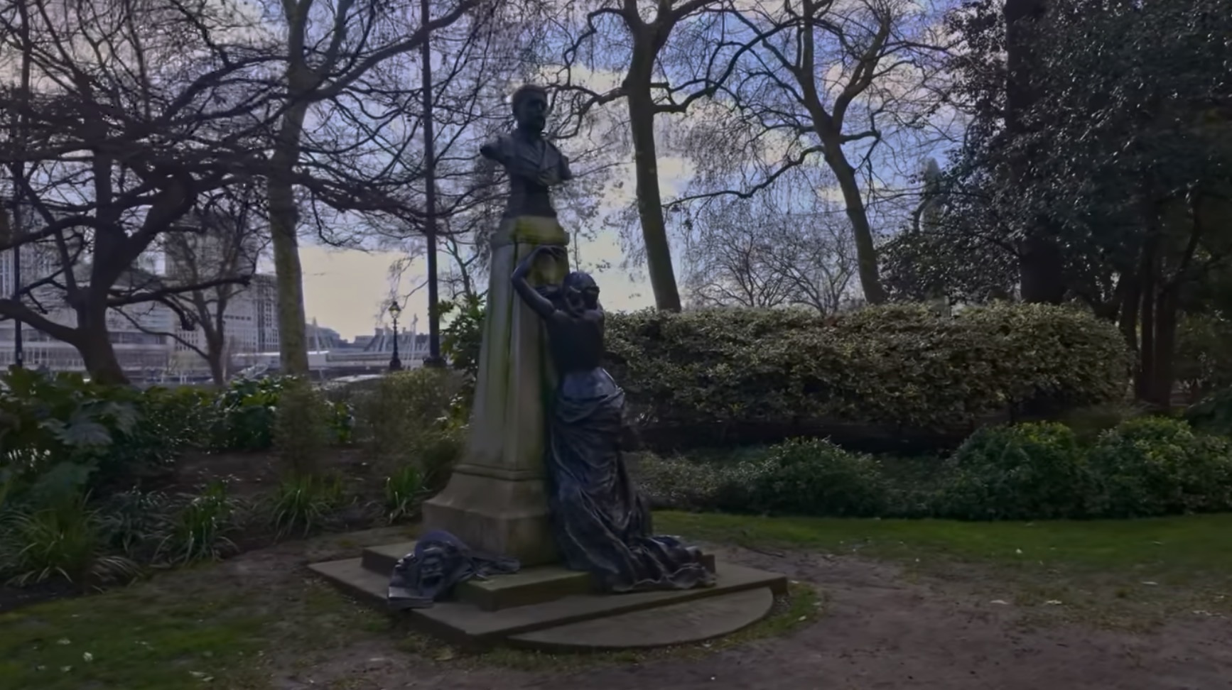 The Arthur Sullivan memorial with a mourning bronze figure beneath the composer's bust, trees and the Thames behind