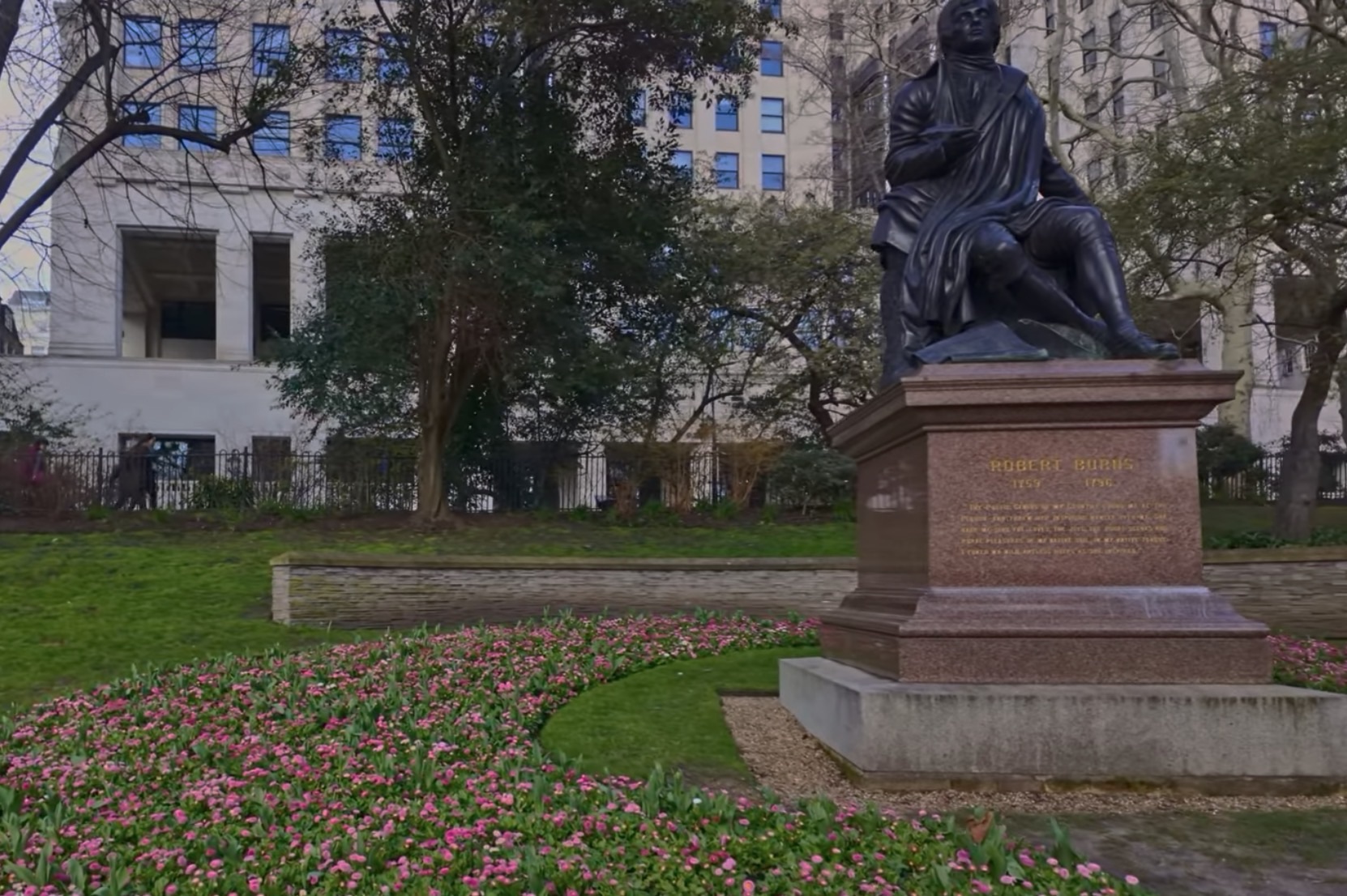 Statue of Robert Burns surrounded by pink and white spring flower beds