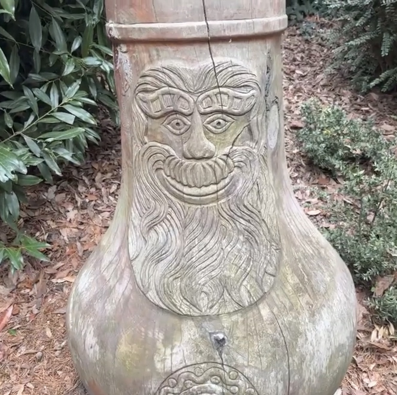 Carved wooden face on a large urn-shaped water feature in Gunnersbury Park