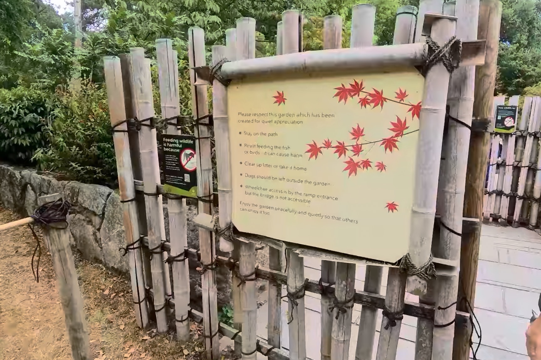 Kyoto Garden etiquette sign on the bamboo fence asking visitors to stay on the path and not feed wildlife