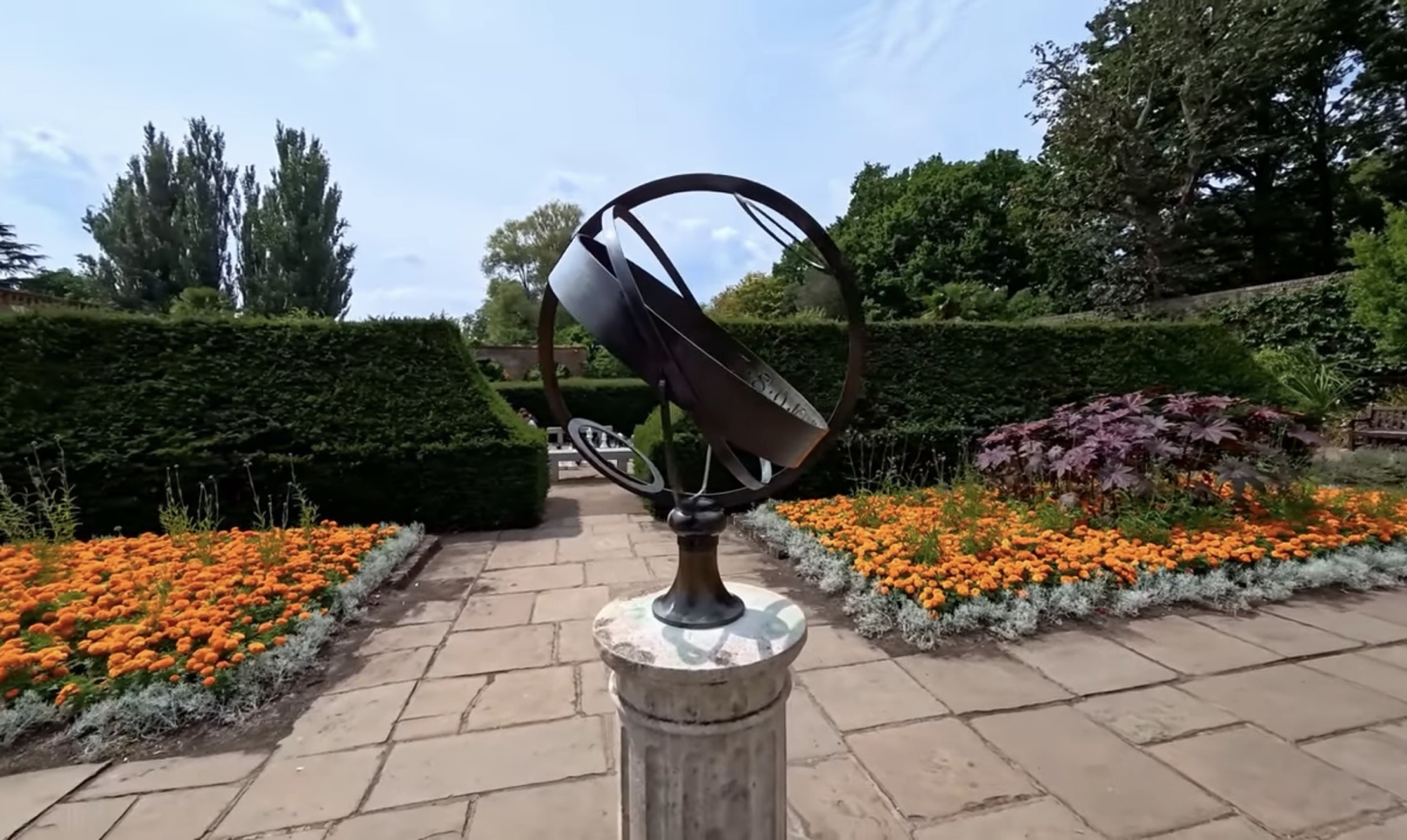Bronze armillary sphere sundial surrounded by marigolds in the Dutch Garden