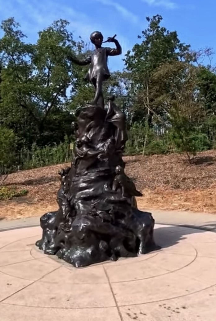 The Peter Pan statue rising above a base of bronze fairies and woodland animals beside the Long Water in Kensington Gardens