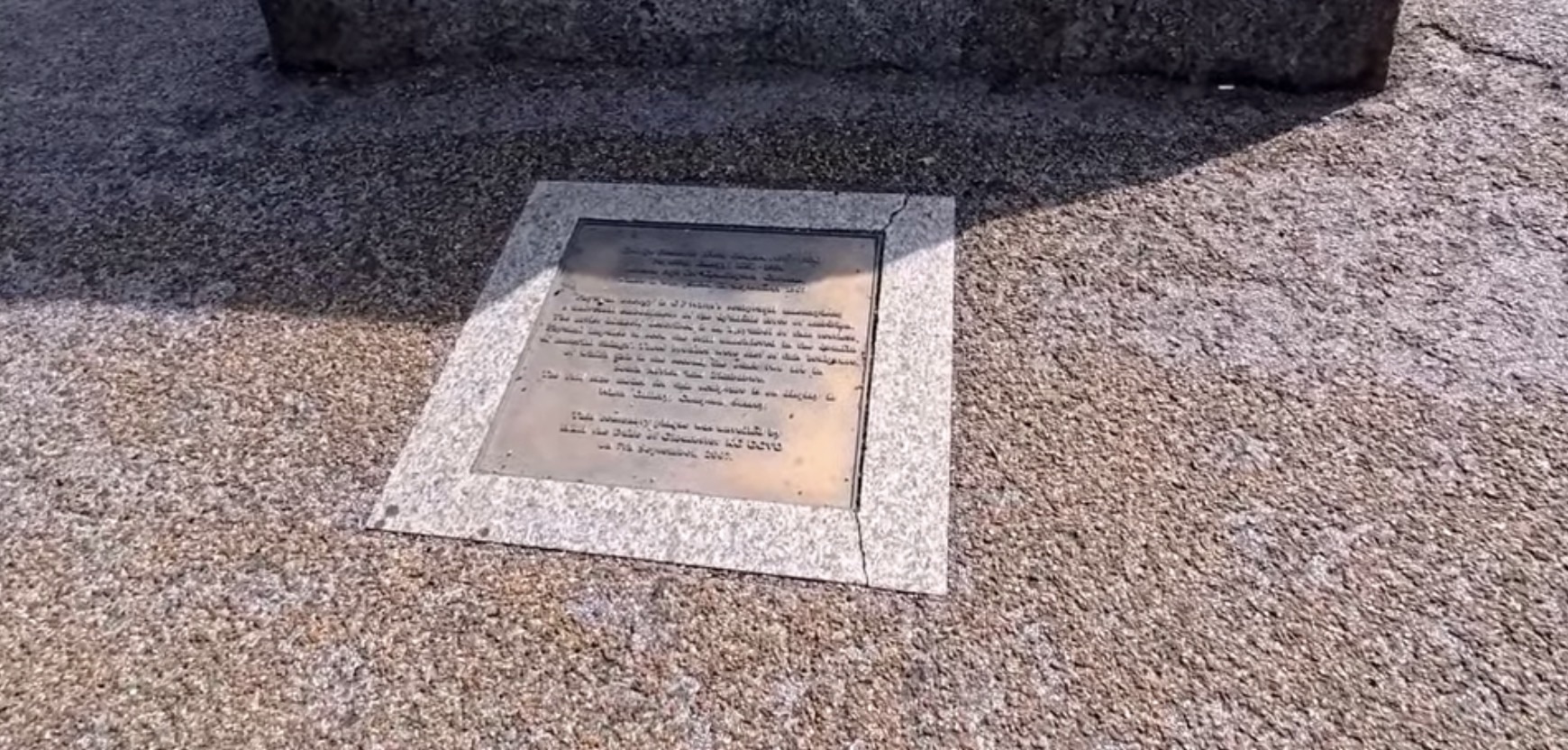 Weathered bronze plaque set into the ground beside the Physical Energy statue in Kensington Gardens