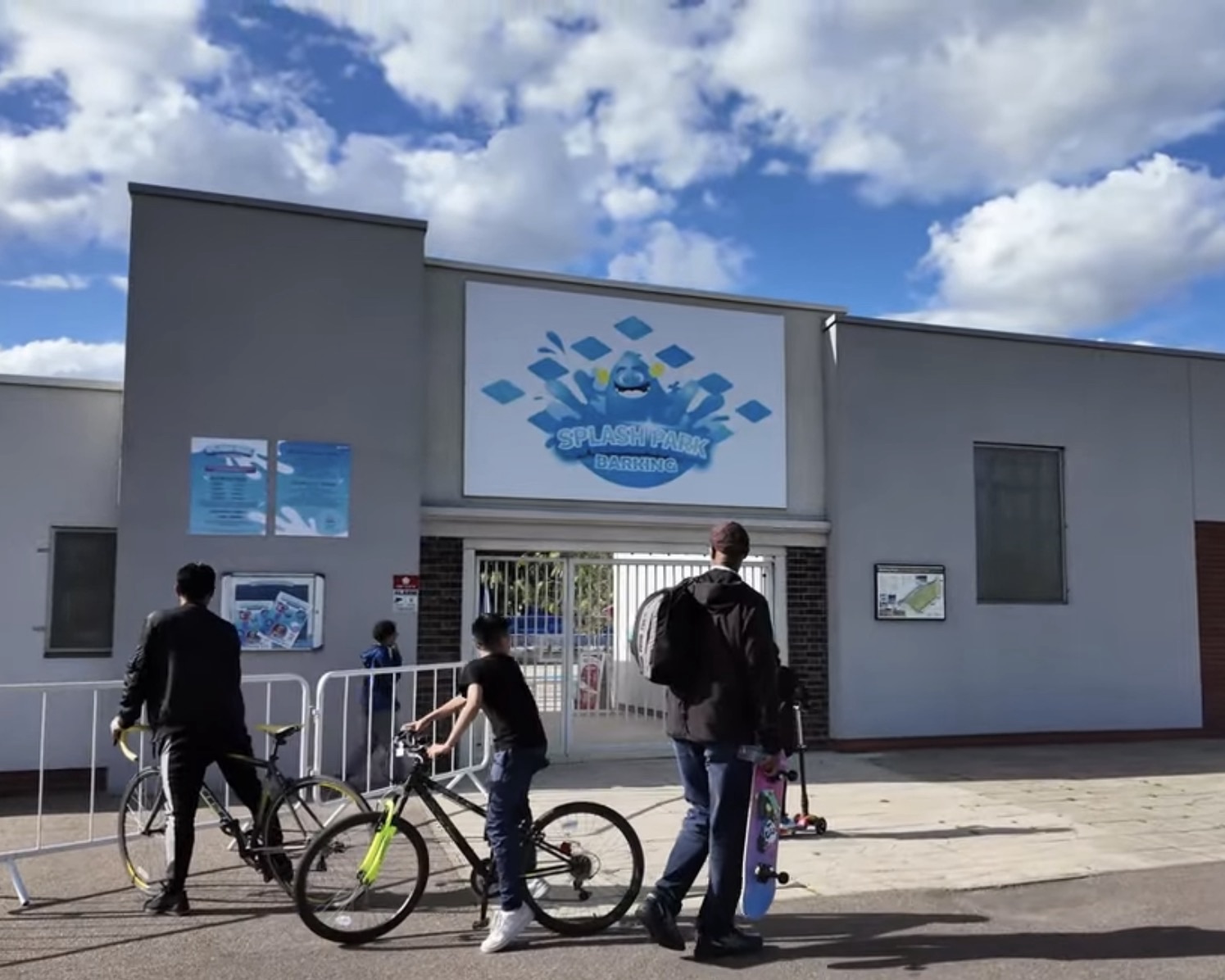 Entrance building of Splash Park Barking with children waiting outside with bikes and scooters