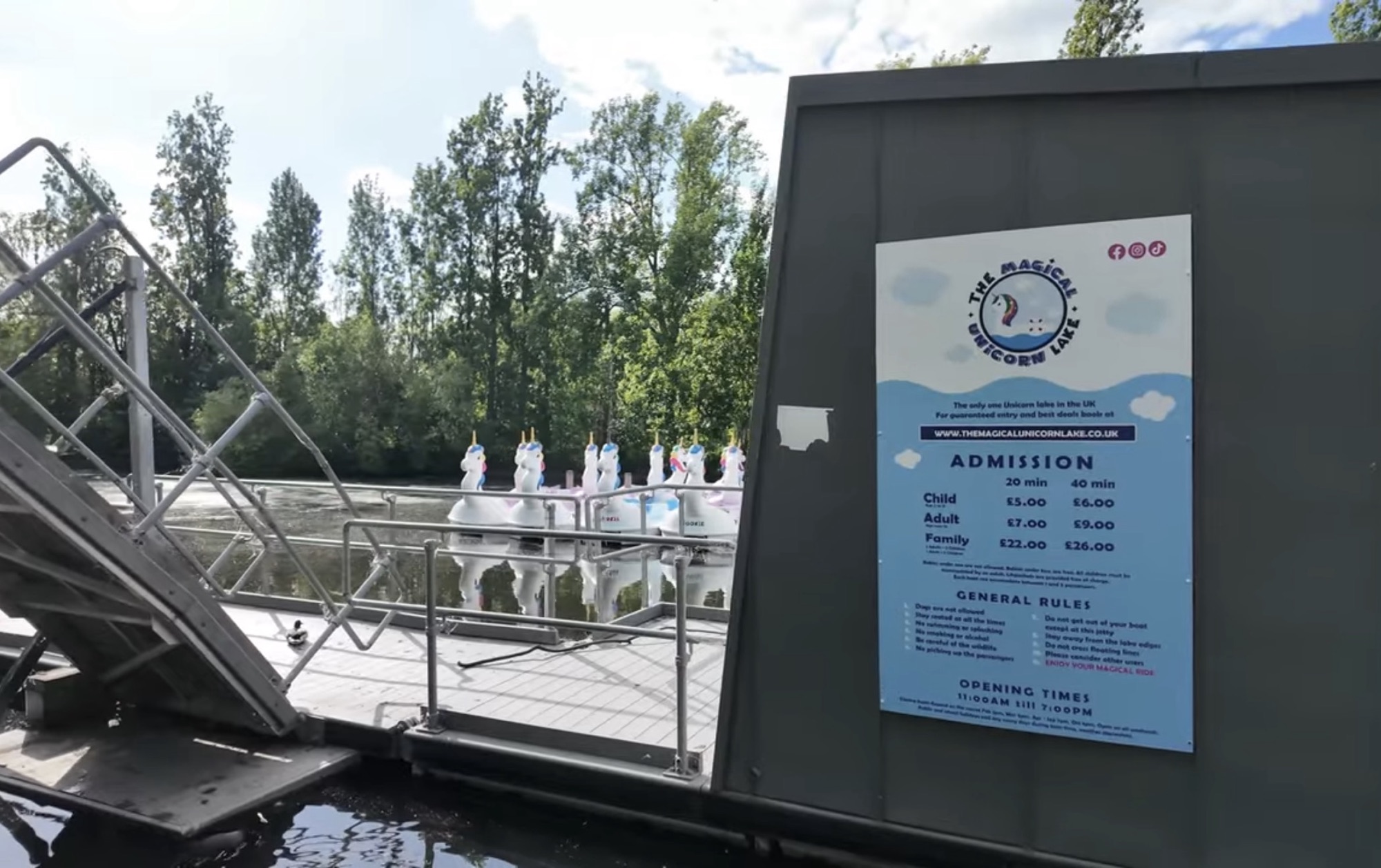 Unicorn-shaped pedalo boats moored on the boating lake with the Magical Unicorn Lake price board