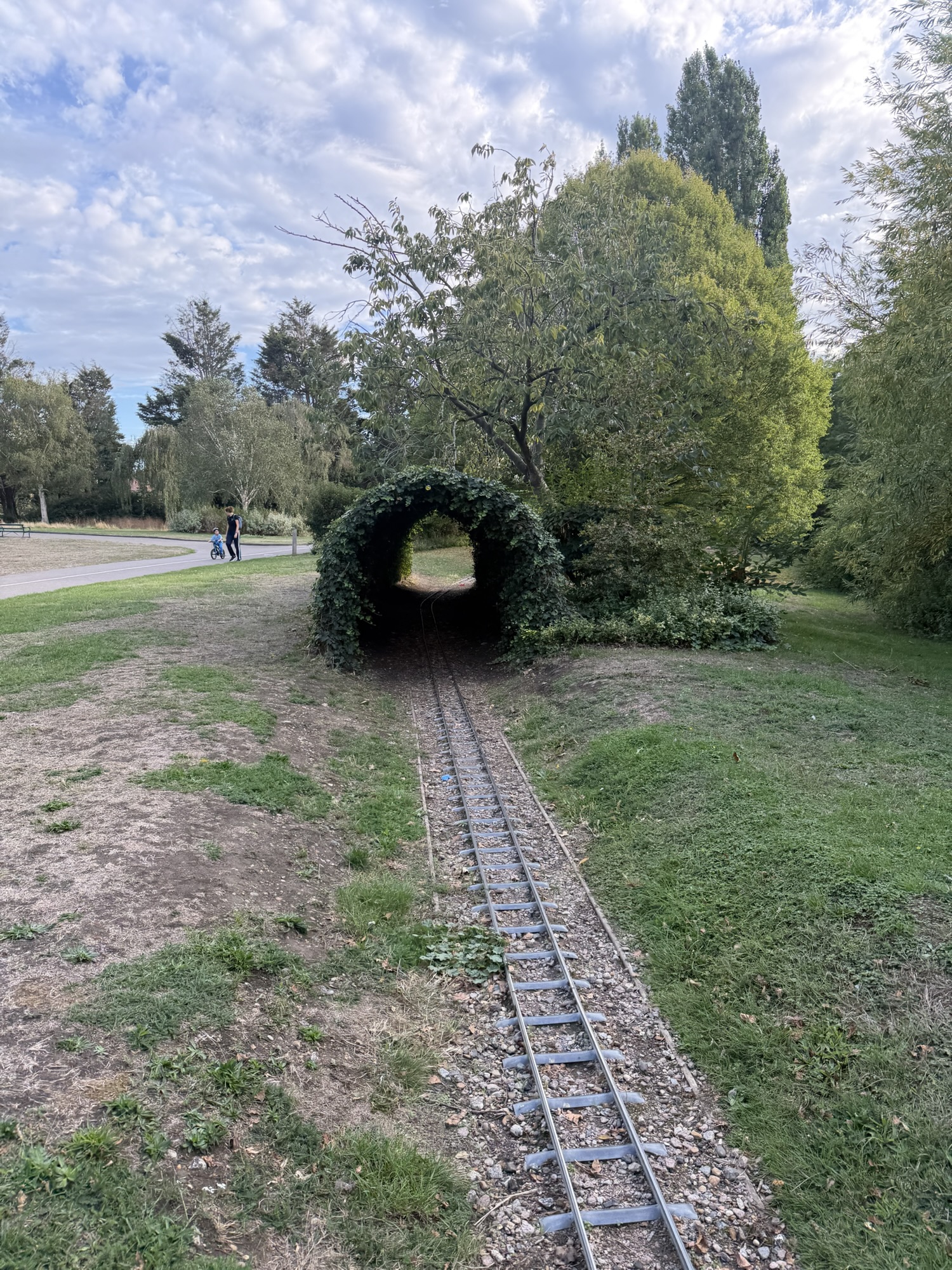 Miniature railway track passing through a green ivy-covered tunnel in Lodge Farm Park