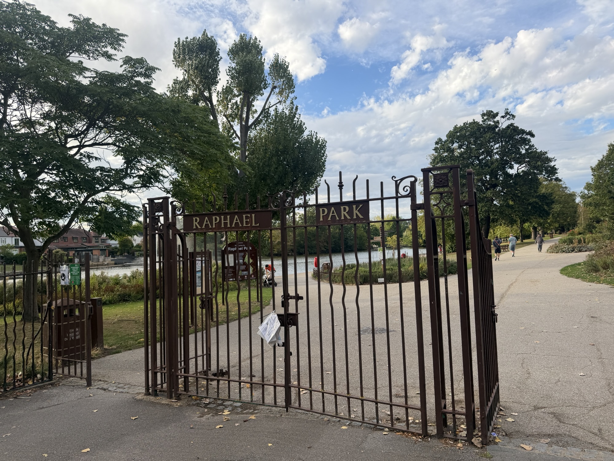 Ornate iron gates reading Raphael Park with the lake visible beyond