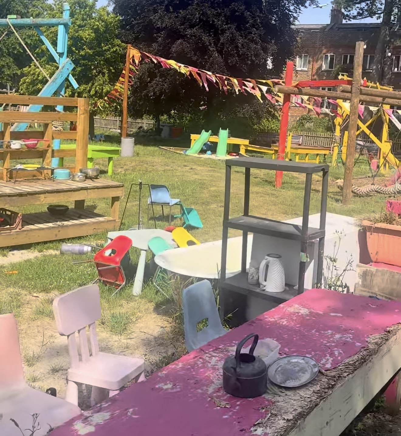Colourful adventure playground with a mud kitchen, bunting, swings and painted play structures