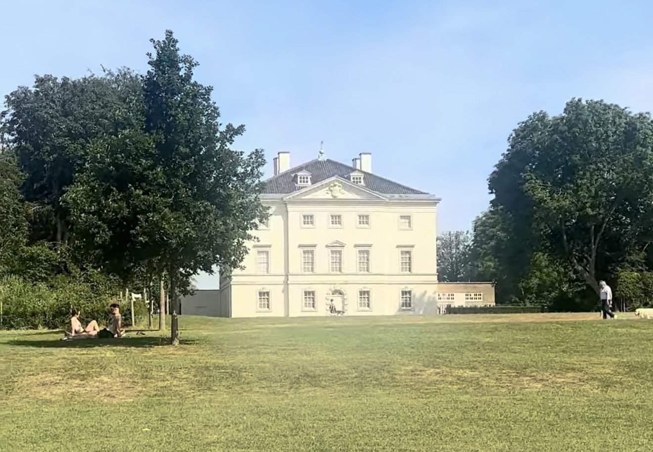 Marble Hill House, a cream Palladian villa, seen across the open lawn with visitors relaxing under the trees