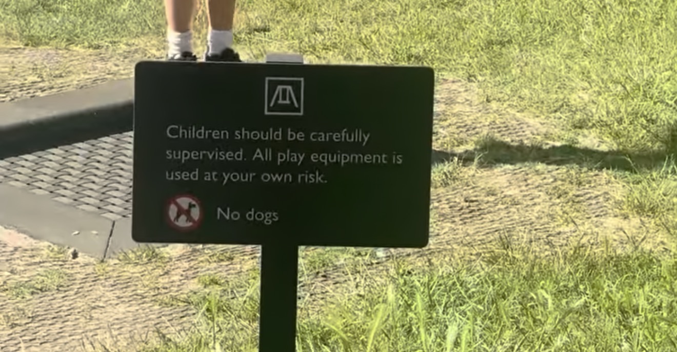 Playground sign asking parents to supervise children closely and stating no dogs are allowed in the play area