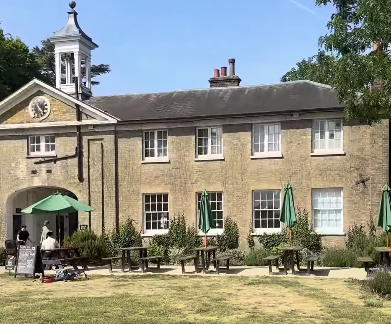 The Coach House with its clock tower and outdoor caf&eacute; seating in Marble Hill Park