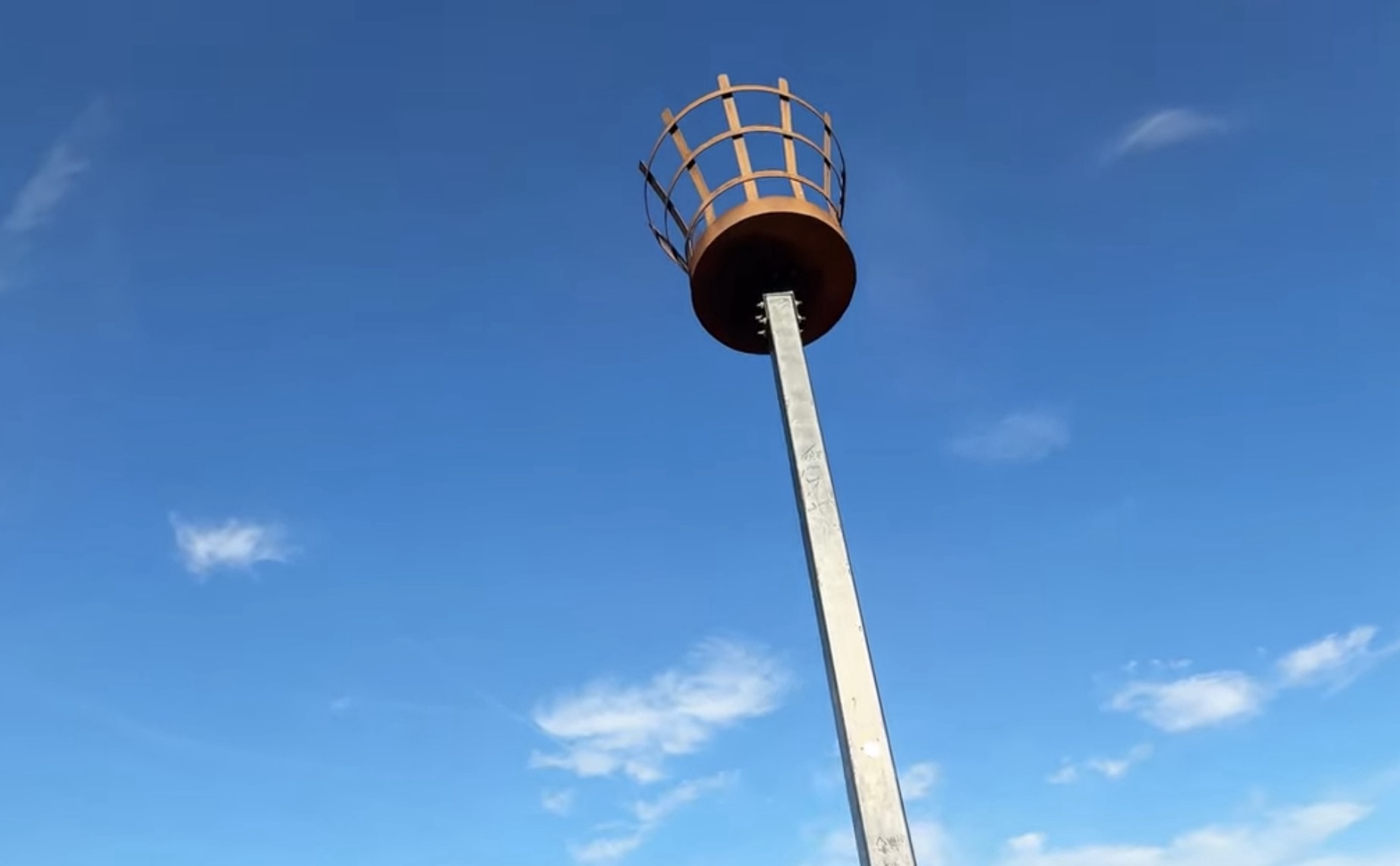 Metal beacon basket on a tall post against a blue sky at the summit of Northala Fields