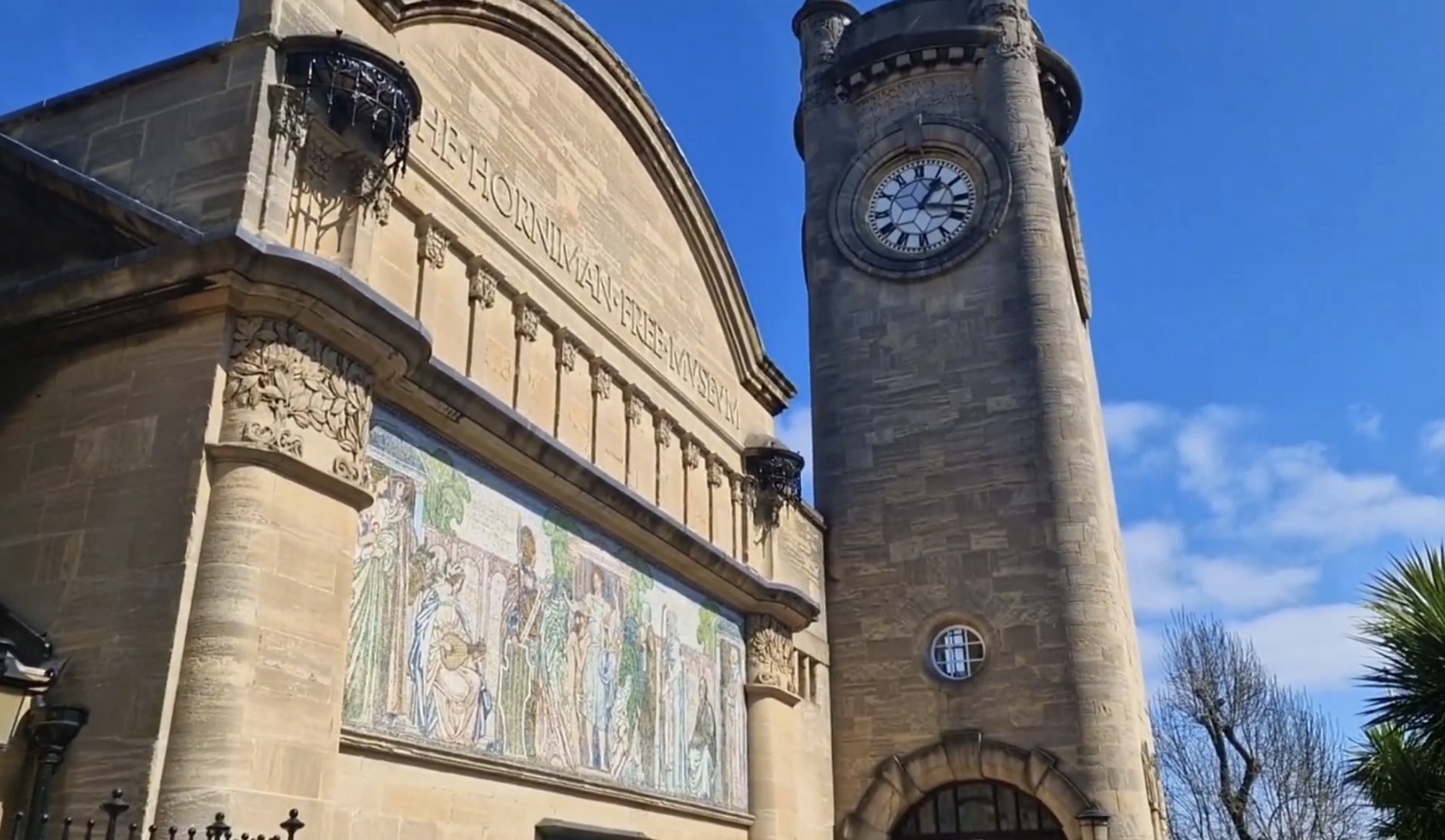 Stone facade of the Horniman Free Museum with its clock tower and the Humanity in the House of Circumstance mosaic