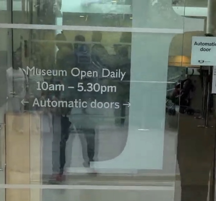 Glass door at the Horniman Museum showing opening hours of 10am to 5.30pm daily