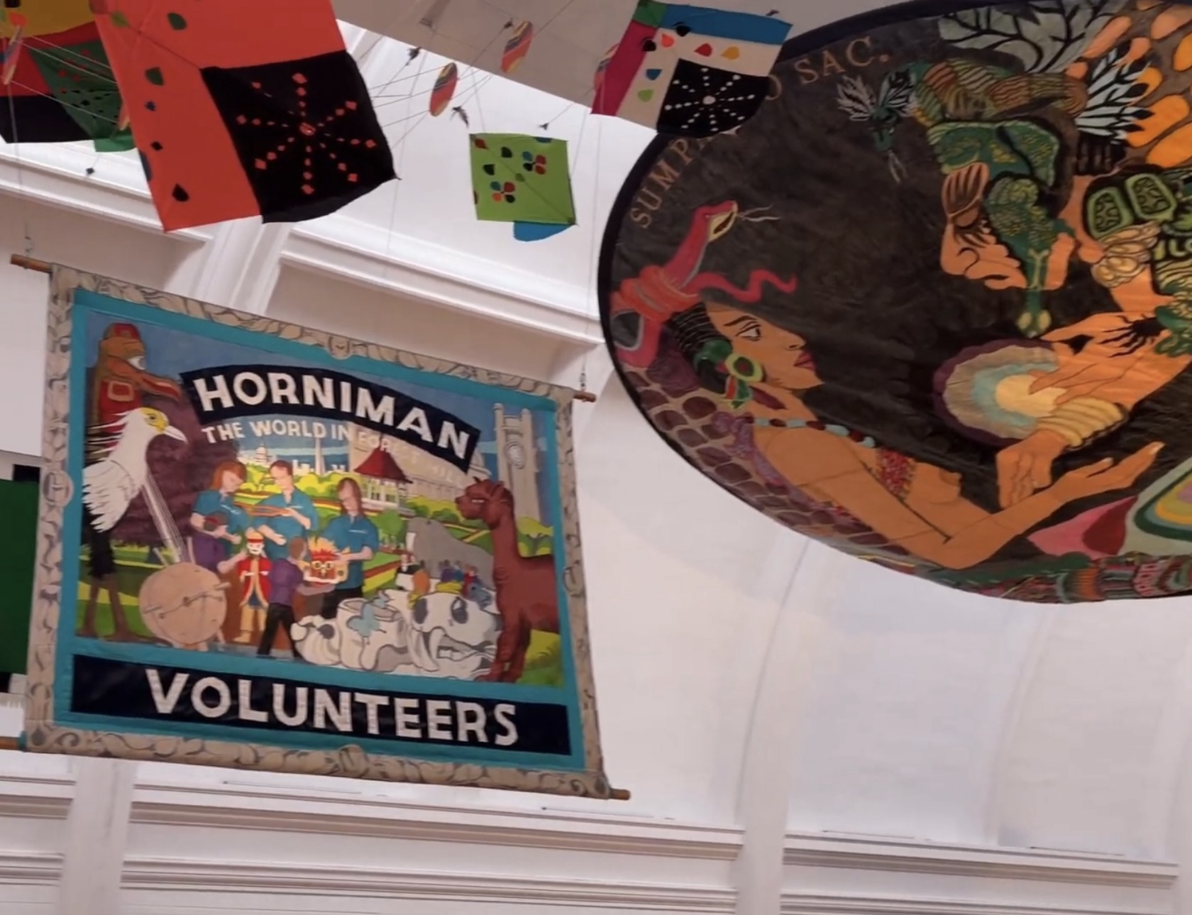 Horniman Volunteers embroidered banner hanging in the gallery beside a large decorated textile