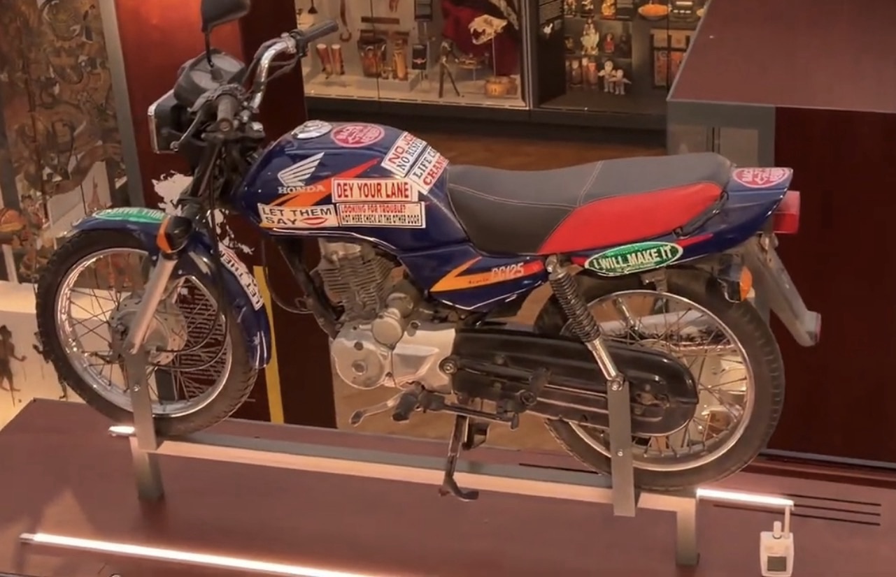 Decorated Honda motorcycle covered in slogan stickers on display in the World Gallery at the Horniman Museum