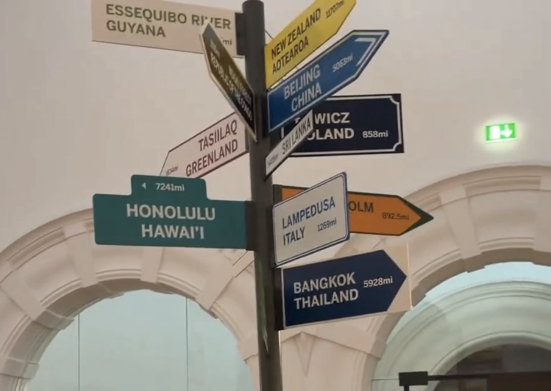 Signpost inside the Horniman Museum pointing to Honolulu, Bangkok, Beijing, Greenland and other places with distances in miles