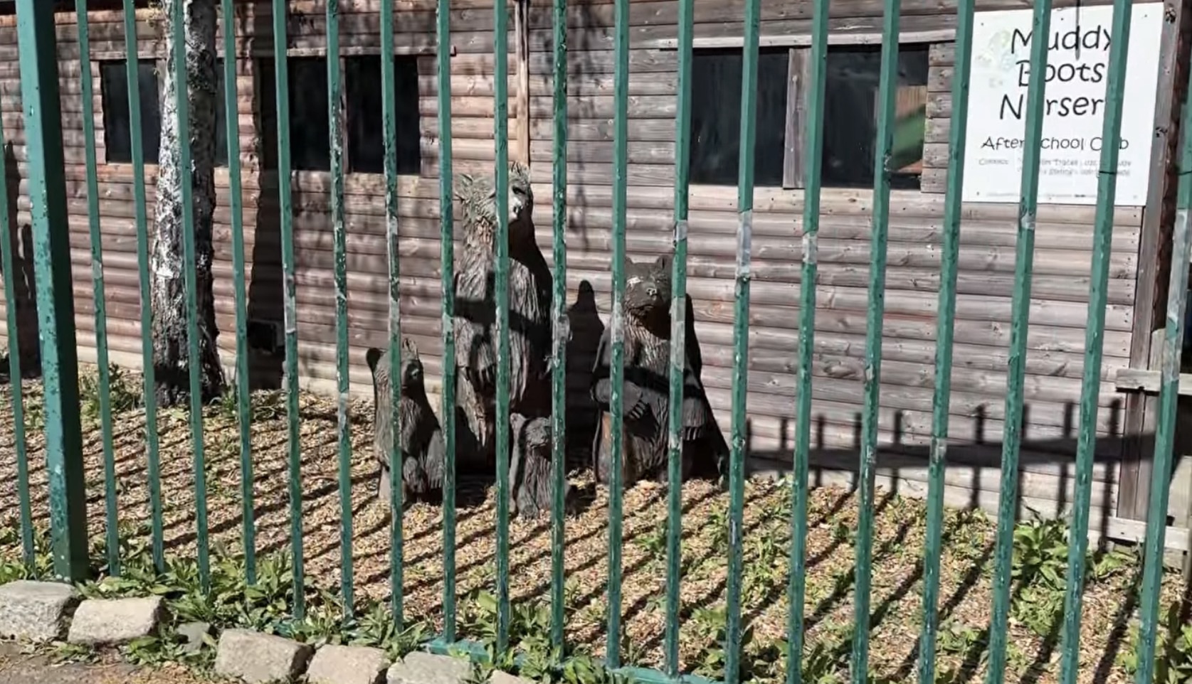 Dark hens behind a green fence outside the Muddy Boots Nursery building at Mudchute
