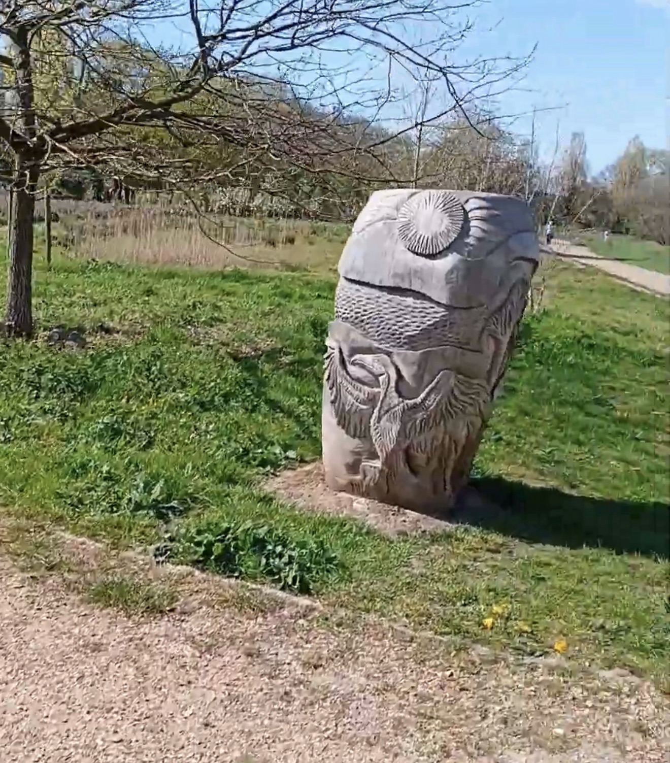 Carved wooden sculpture showing a sun, water ripples and a wading bird in Boston Manor Park