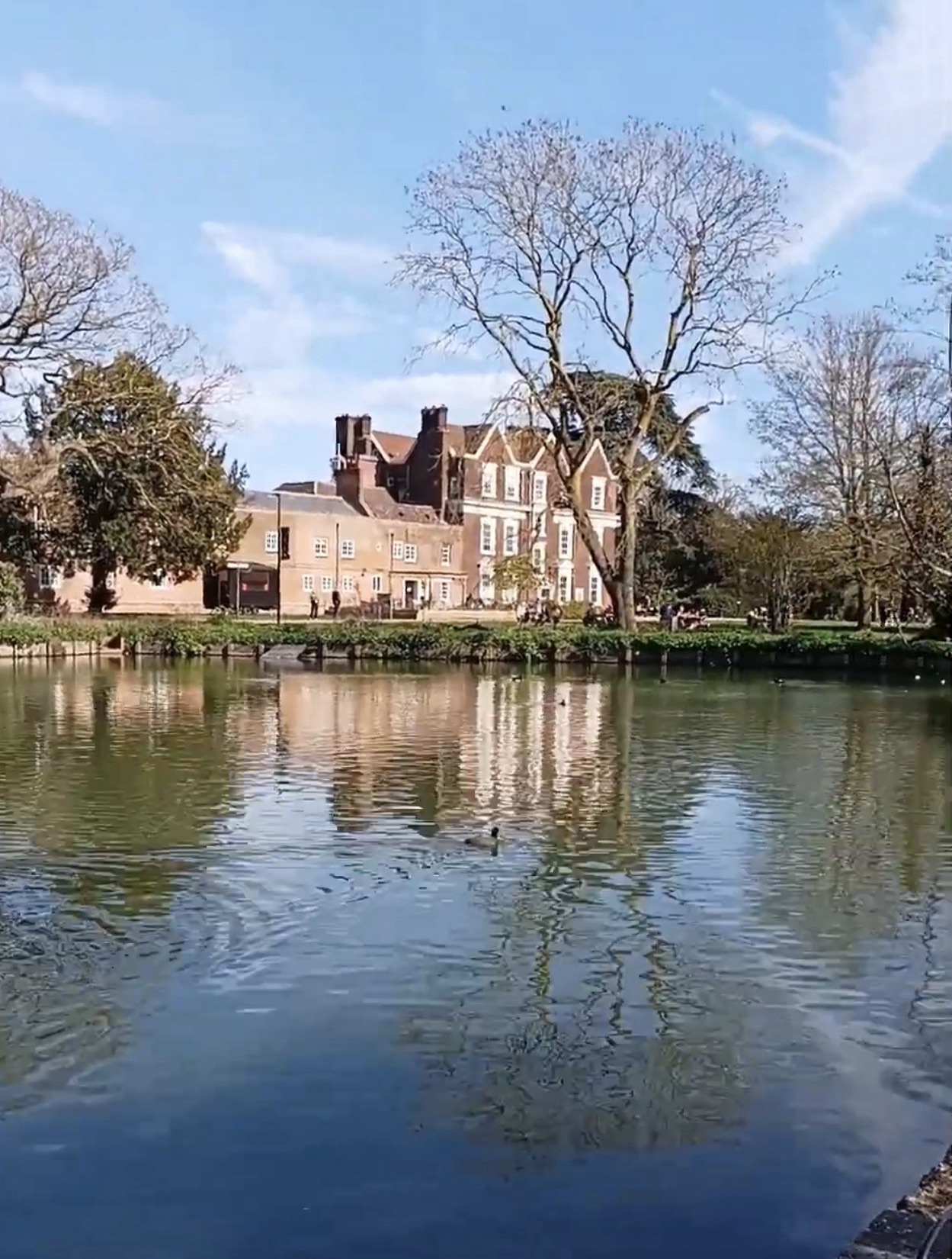 Red-brick Boston Manor House reflected in the lake at Boston Manor Park on a sunny day