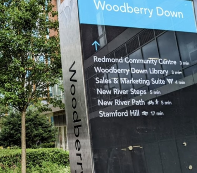 Steel wayfinding totem in Woodberry Down listing the community centre, library, New River Steps, New River Path and Stamford Hill with walking times