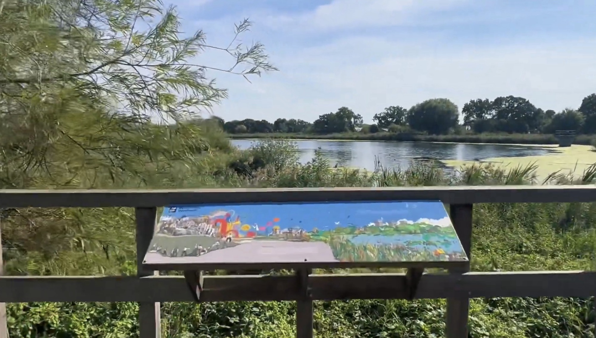 Colourful painted panorama panel on a wooden railing overlooking the reservoir and reeds