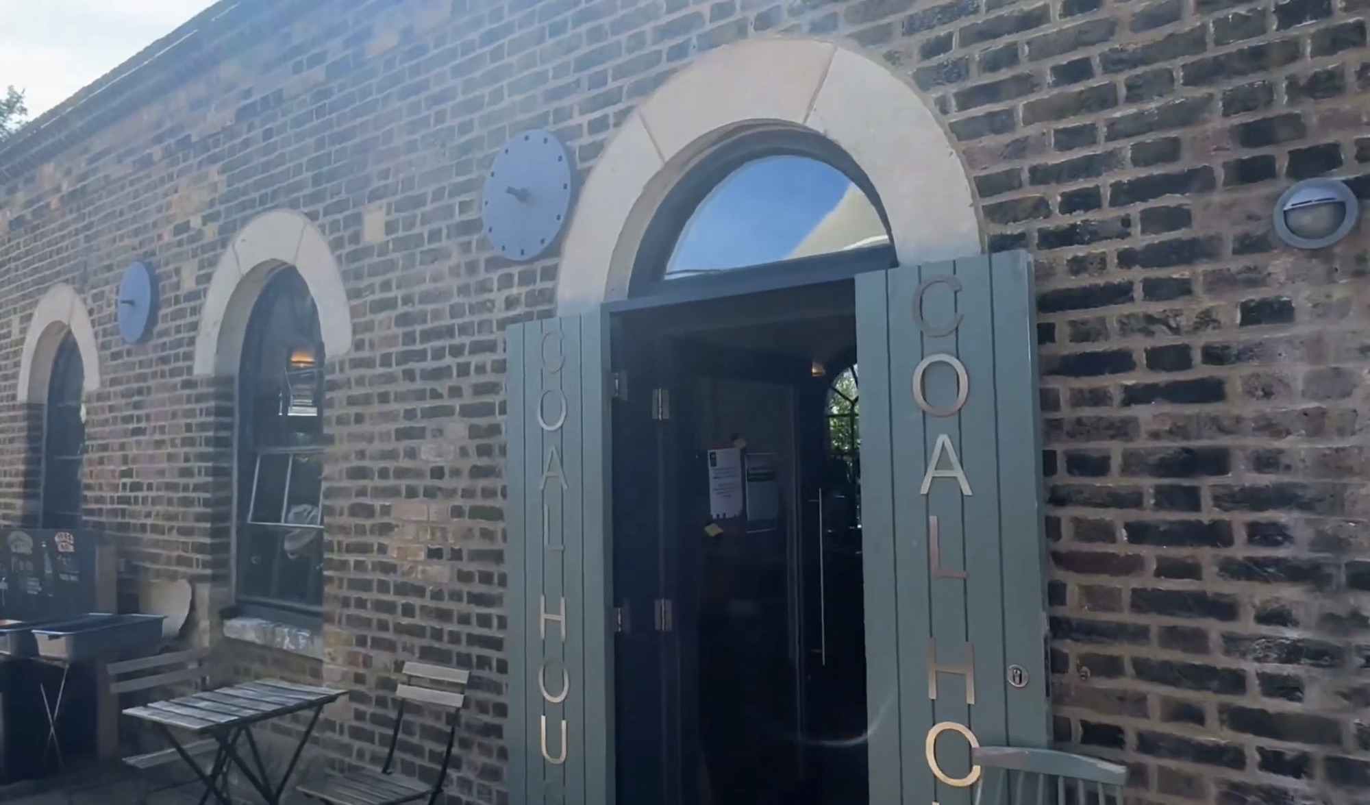 Brick façade of the Coal House café with arched windows, round clocks and the word Coal House on the open shutters